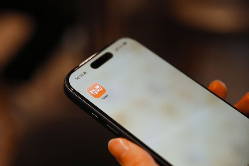 ショッピングアプリのアイコンが表示されたスマートフォンを持つ手