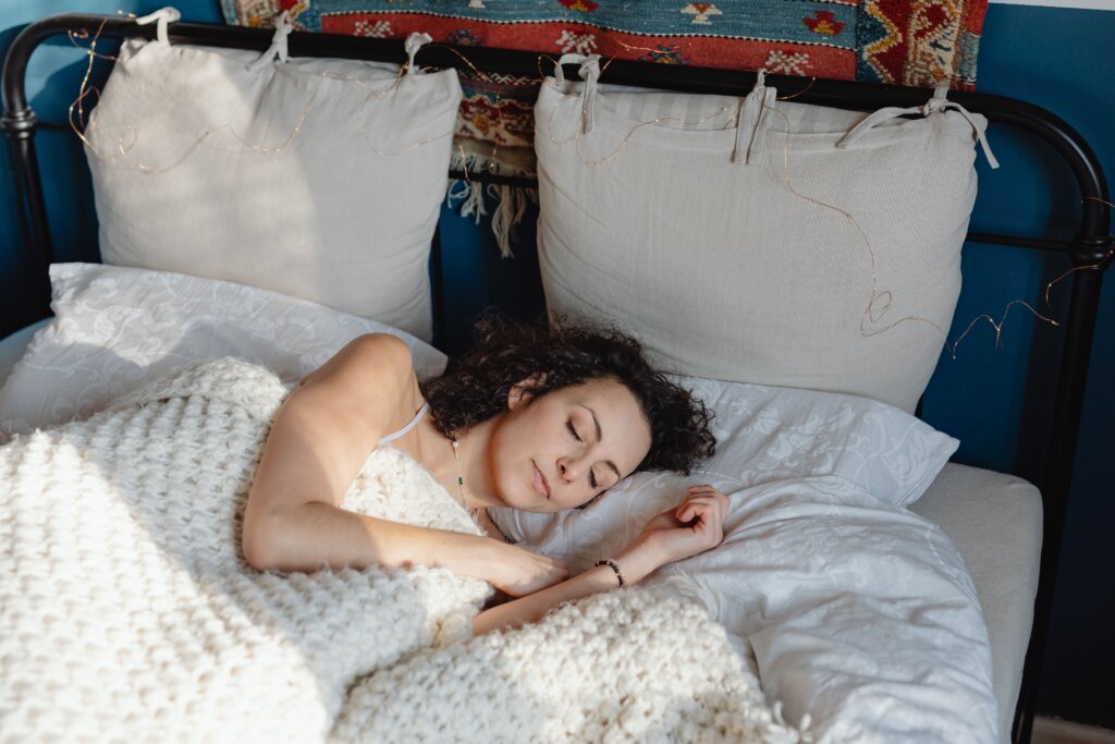 白いブランケットにくるまって眠る女性